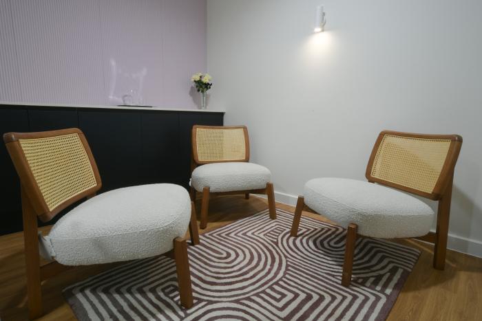 One lilac wall, one white wall and 2 white wicker chairs arranged in a circle