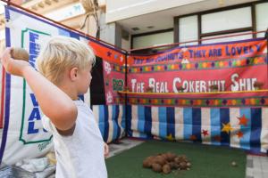 Summer High Street Event, week 1. A little boy throwing is playing coconut shy.