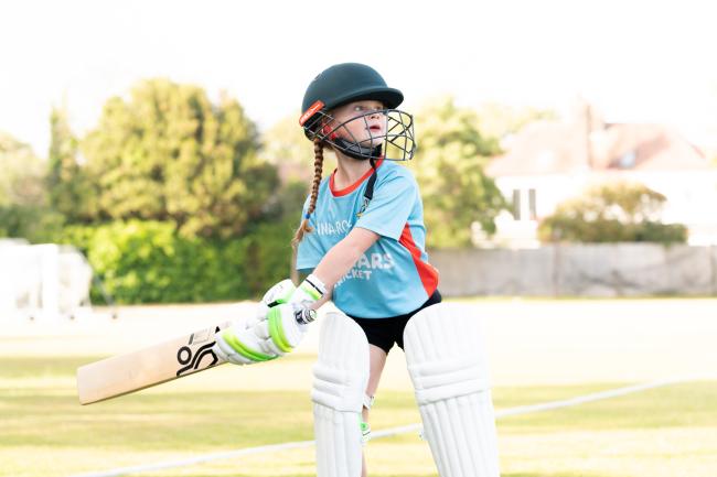 Girl playing cricket in full kit