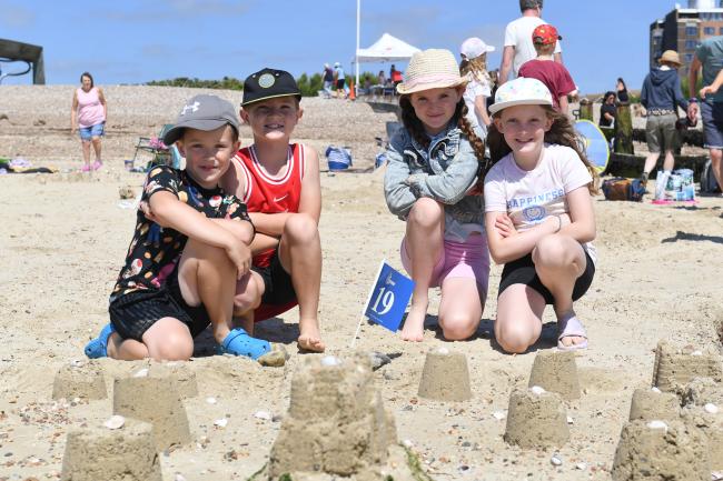 Sandcastle Competition 2024 children sitting on the beach with sandcastles