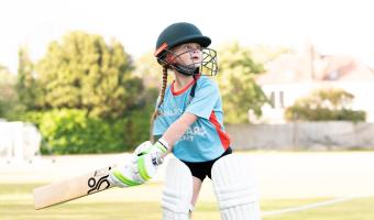 Girl playing cricket in full kit
