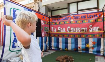Summer High Street Event, week 1. A little boy throwing is playing coconut shy.